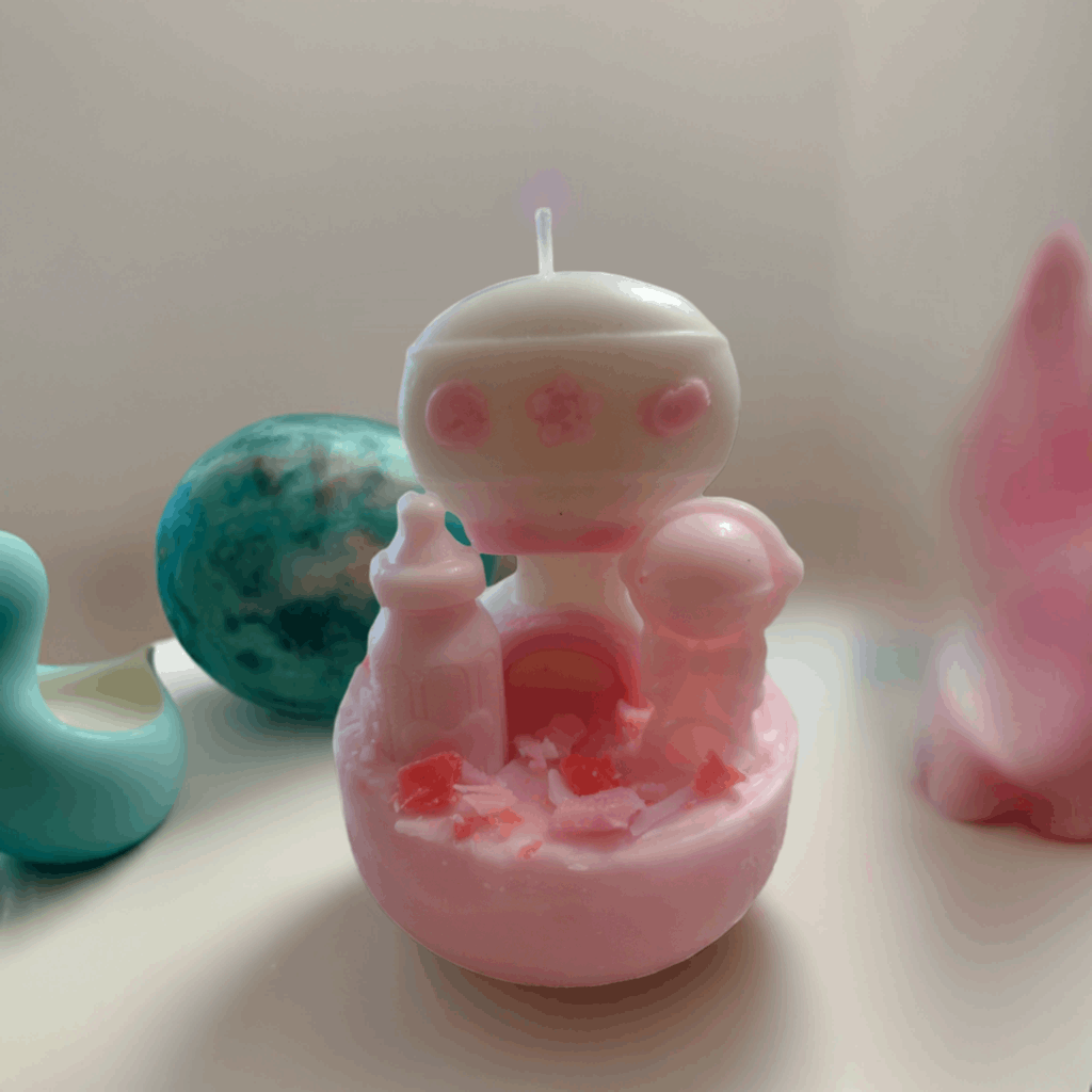 Whimsical pink robot candle with rattle function – eco-friendly and fun.